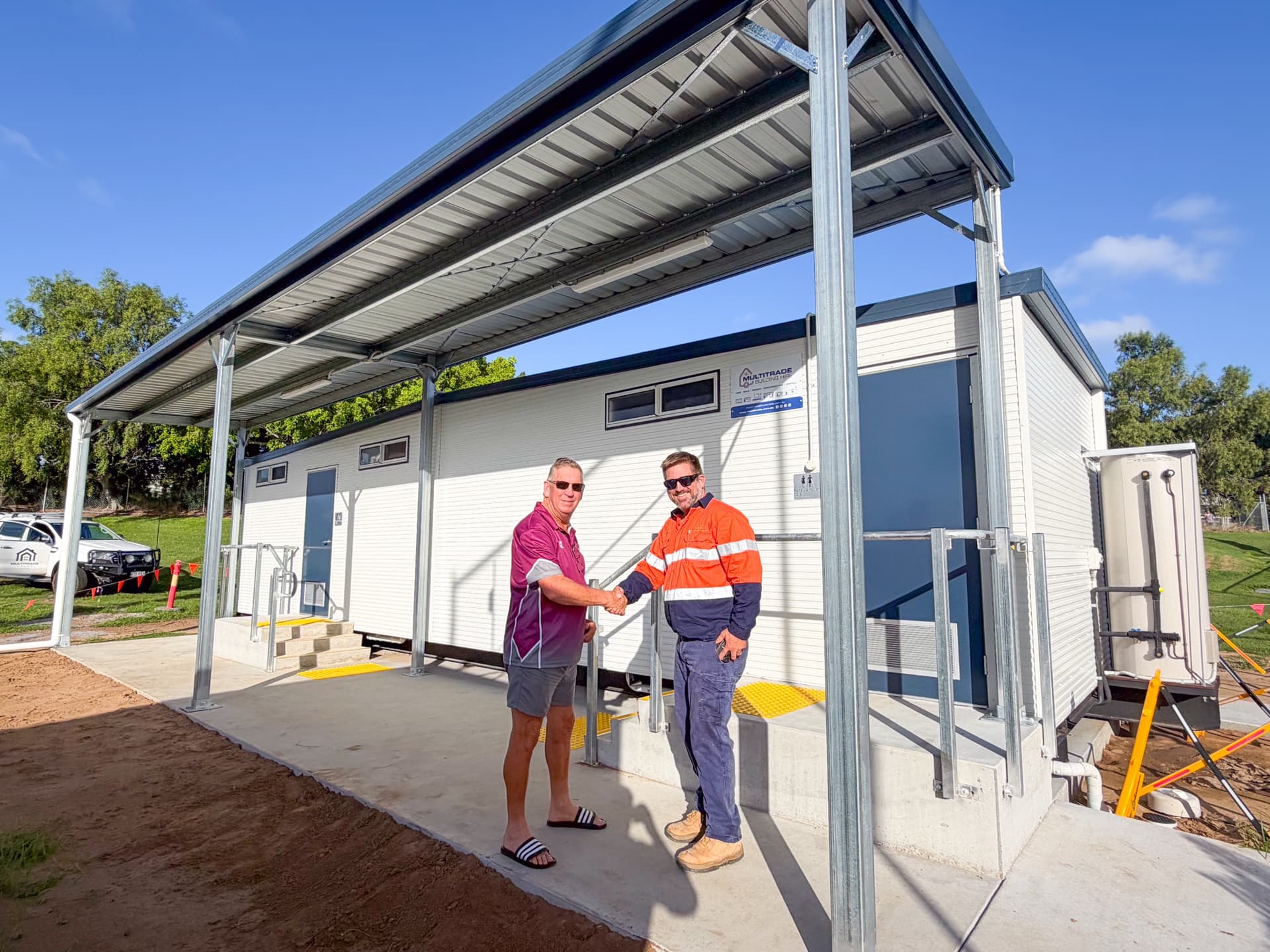 Client and Multitrade representative in front of an amenities building with a covered entry