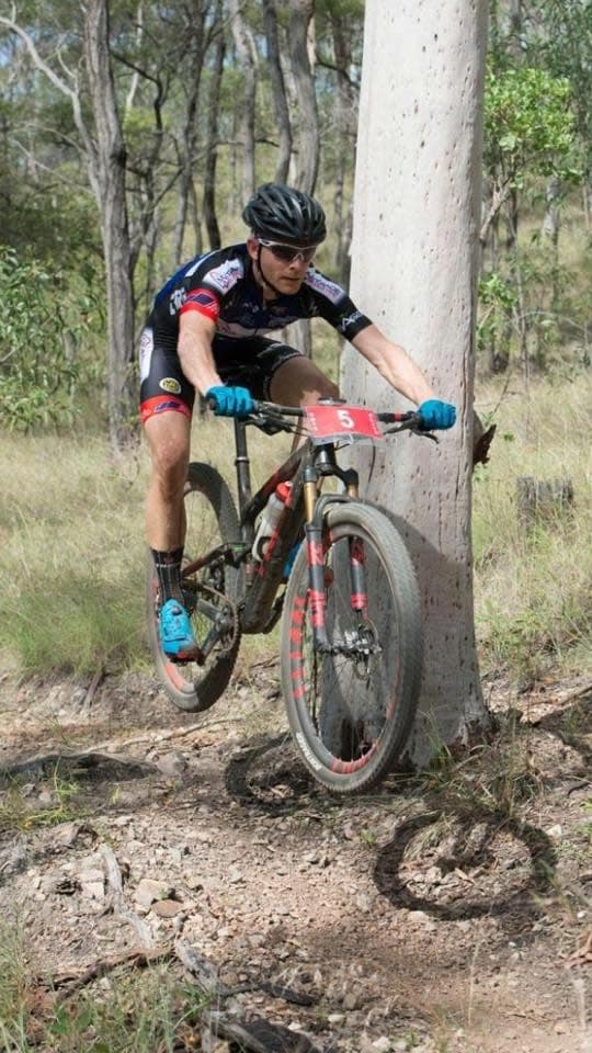 Mountain-bike rider on a bush trail wearing a Multitrade-branded jersey