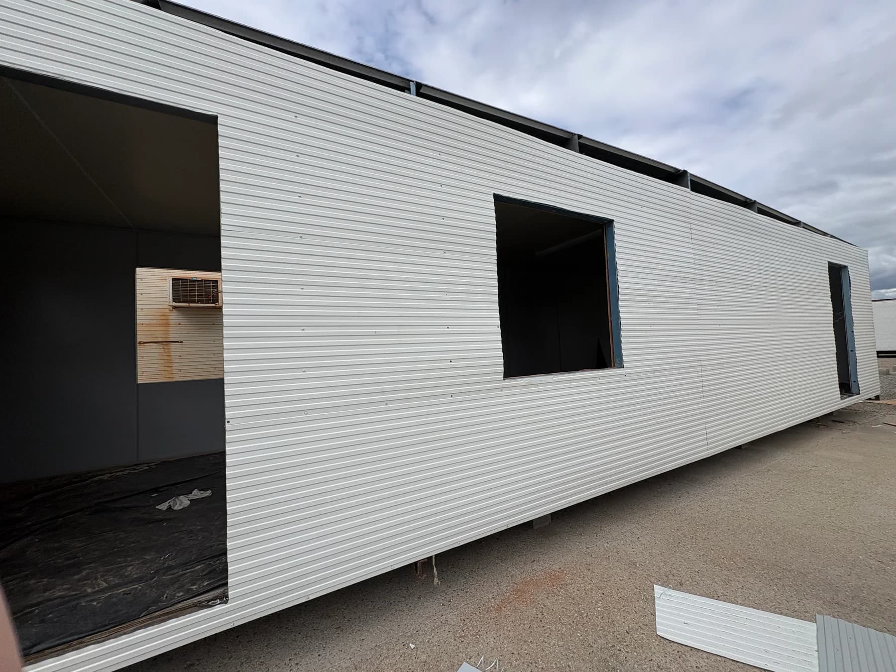 Portable building with replacement cladding and unfinished door and window openings