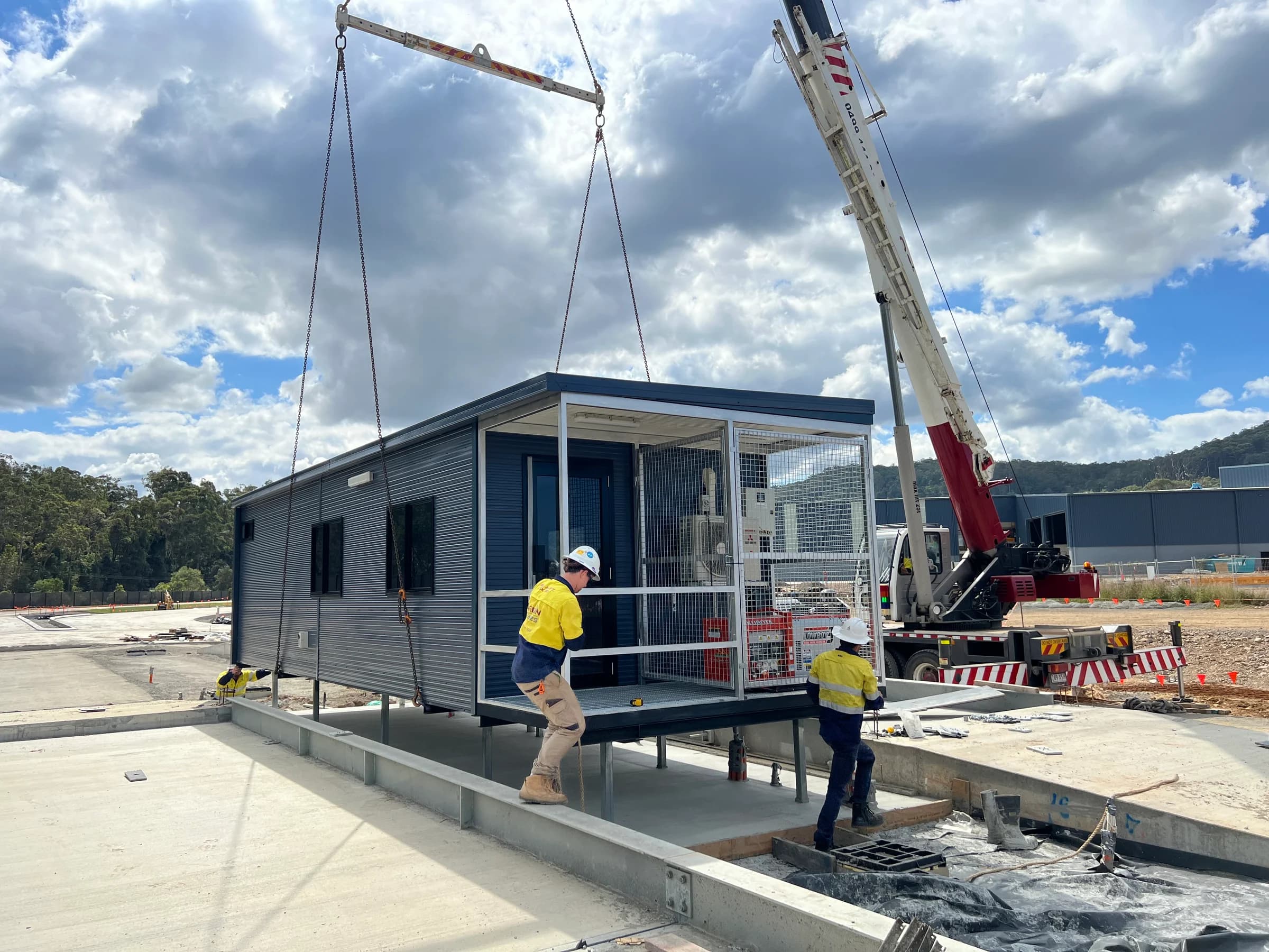Crew and crane positioning a portable building during installation