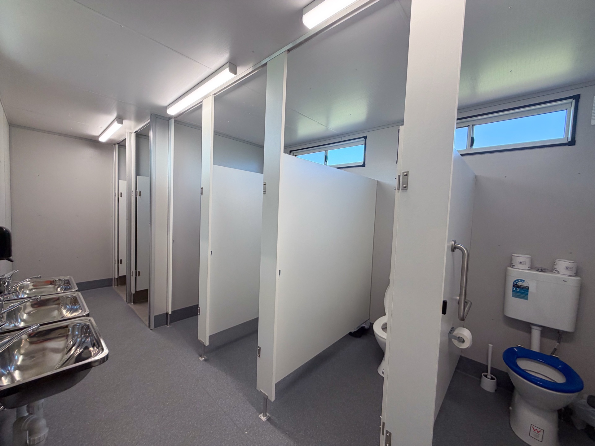 Interior — multiple toilet stalls with S/S basins